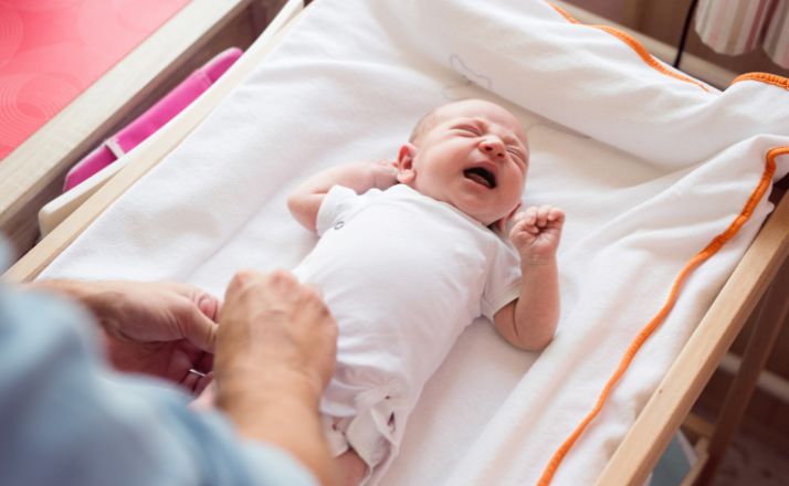 baby crying on a changing table with mom nearby as an example of baby safety tips