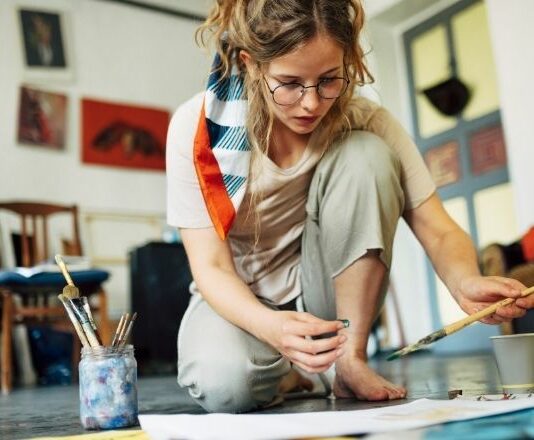 woman sitting on the floor painting as one example of hobbies for women