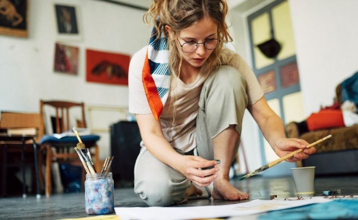 woman sitting on the floor painting as one example of hobbies for women