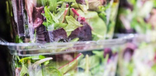 Macro closeup of mixed green salad in boxes on display