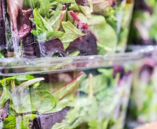 Macro closeup of mixed green salad in boxes on display