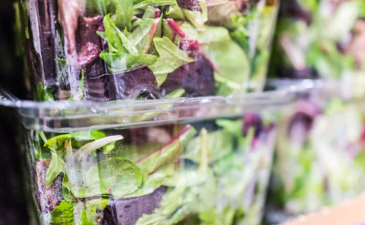 Macro closeup of mixed green salad in boxes on display