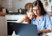 single mom working at computer with daughter by her side