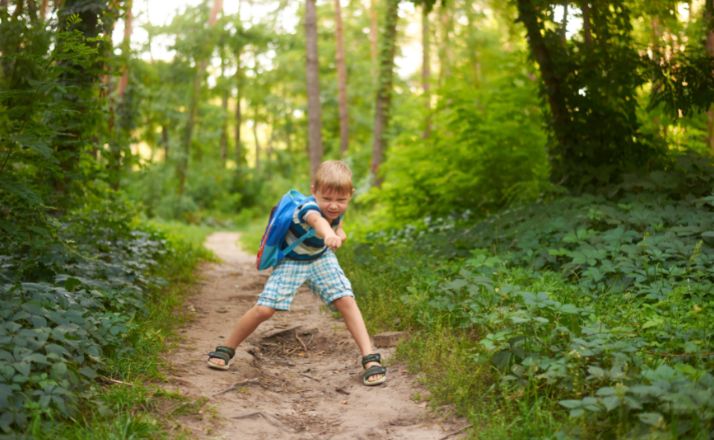 boy playing on a trail through the woods as part of his unschooling