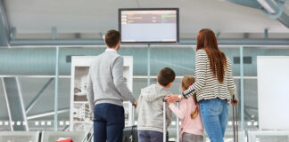 Family looks at the scoreboard in the airport terminal and looks for the right flight