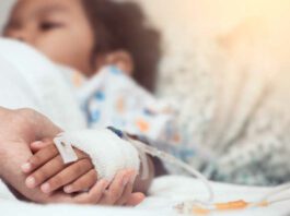 Mother hand holding child hand who have IV solution in the hospital with love and care