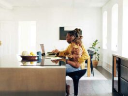 Young mom sitting with her daughter while working from home.