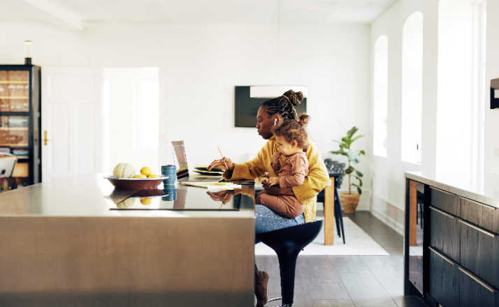 Young mom sitting with her daughter while working from home.