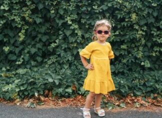 Toddler with yellow dress, sunglasses, and hands on her hips