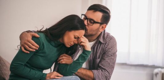 Husband comforting distraught wife with PTSD to promote trigger warnings