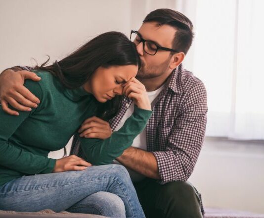 Husband comforting distraught wife with PTSD to promote trigger warnings