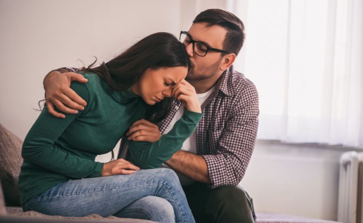 Husband comforting distraught wife with PTSD to promote trigger warnings