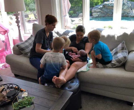 mom with newborn, midwife and older kids sitting on couch