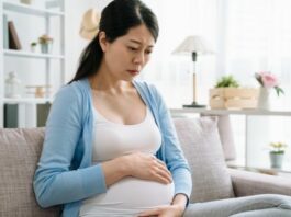 woman looking down at her pregnant belly suffering from perinatal depression