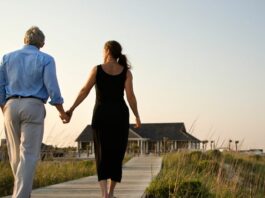 woman holding hands with a widower as they walk on a boardwalk