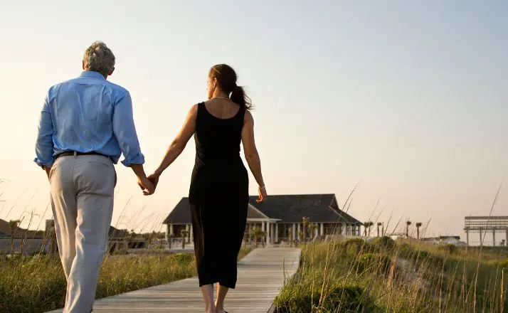 woman holding hands with a widower as they walk on a boardwalk