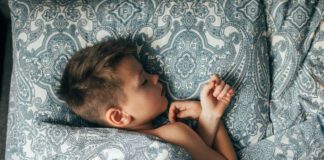 Cute boy sleeping in bed. Child 6-7 years old smiling, having a good dreams