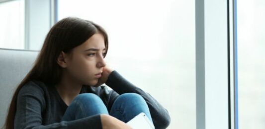 teen with depression looking out window