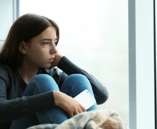 teen with depression looking out window
