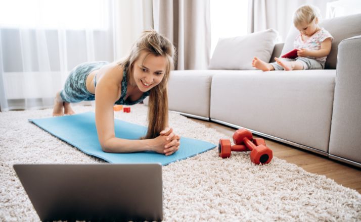 mom doing her workout routine at home while child sits on couch