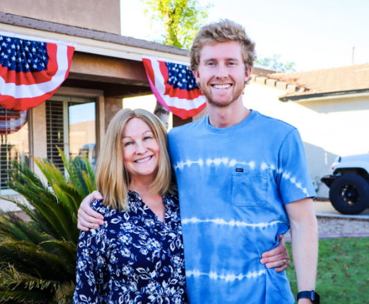 Photo of mother and son standing in front of a house.