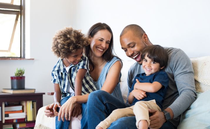 millennial parents laughing with their two kids in their home