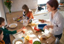 A mother of three little children packing school lunches in the kitchen at home.