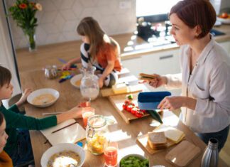 A mother of three little children packing school lunches in the kitchen at home.