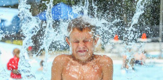 Boy at waterpark being hit with icy cold water