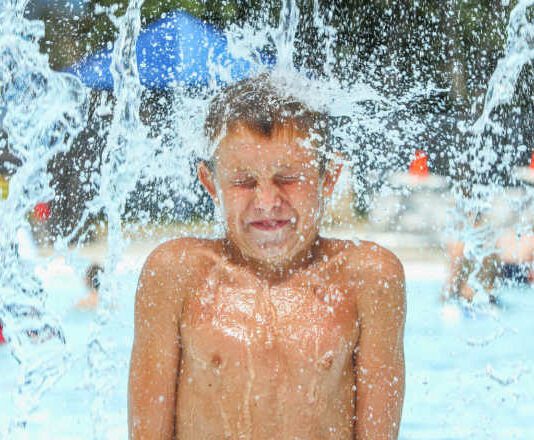 Boy at waterpark being hit with icy cold water