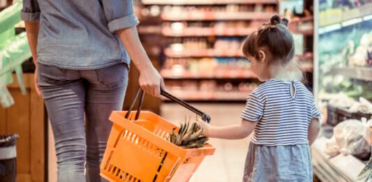 mom and daughter shopping in grocery store because of high cost of having kids