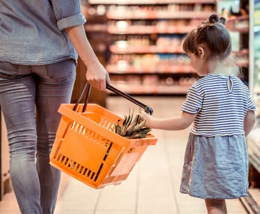 mom and daughter shopping in grocery store because of high cost of having kids