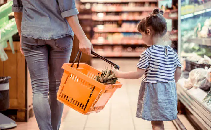 mom and daughter shopping in grocery store because of high cost of having kids