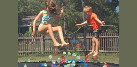 two kids on trampoline with water balloons