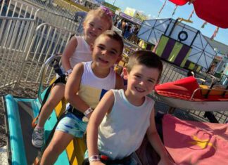 three kids sitting on fair rides