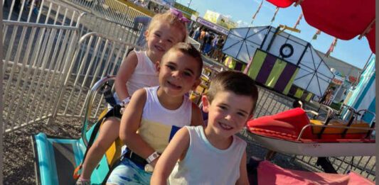 three kids sitting on fair rides