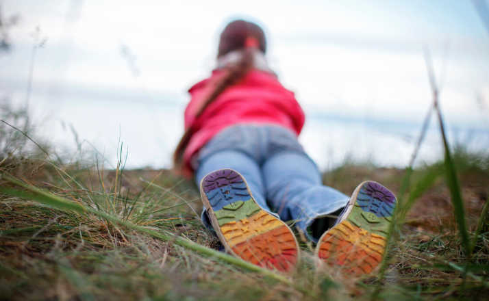 little girl with rainbows on shoes lying in grass lgbtq community