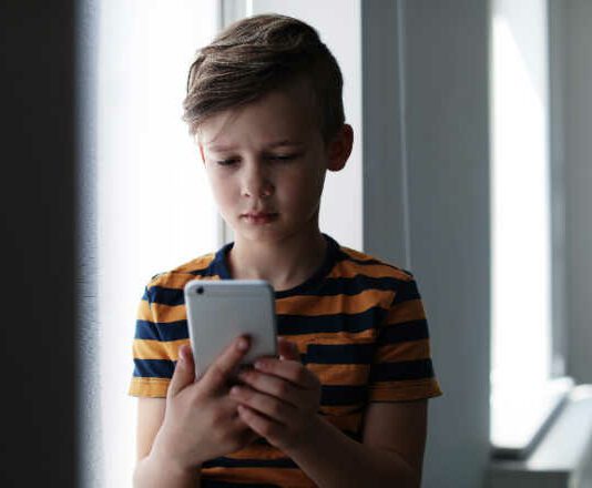 Sad little child with smartphone indoors. young kids on screens