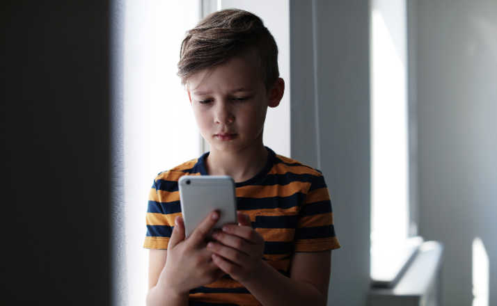 Sad little child with smartphone indoors. young kids on screens