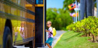 photo of small caucasian boy on curb getting onto school bus