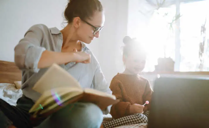 woman with book helping her child with homework