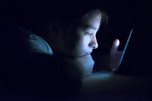 Teenager sending email from smart phone in her bed, Typing text message on smartphone. young cell phone addict teen  awake at night in bed using smartphone for chatting cyberbullying